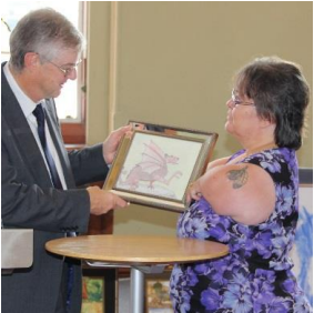 Julie Jean presenting her Dragon picture to Mark Drakeford