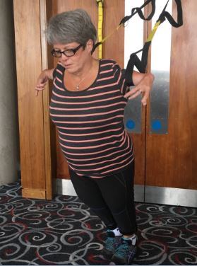 Simone demonstrating how she exercises with resistance bands on her arms, pulling against a door where the bands are fixed