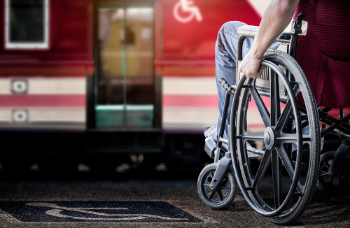 A person in a wheelchair on a station platform in front of an accessible entrance to a train