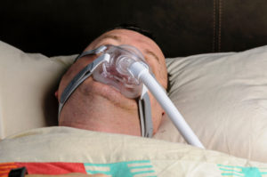 man sleeping with CPAP mask on for sleep apnoea