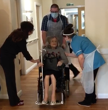 elderly lady being pushed in a wheelchair by an orderly coming out of hospital after recovering from Covid