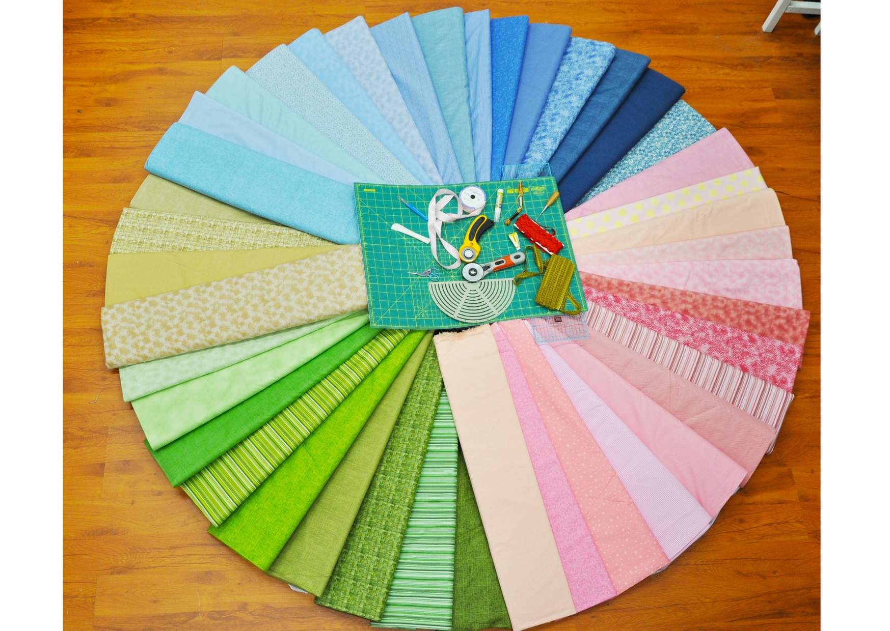 Colour wheel display of material pieces used for patchwork with sewing tools