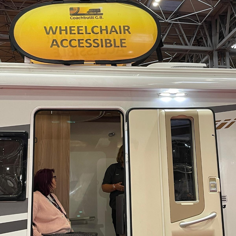 wheelchair accessible caravan with its wide door open showing a lady sitting inside in her wheelchair