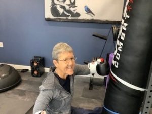 Activity Champion Jean exercising by hitting her punch bag with boxing gloves on