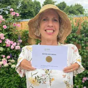 Sue in her sun hat holding her Silver-Gilt Medal