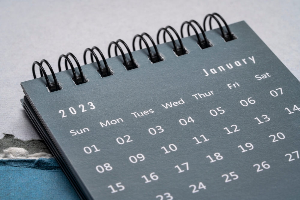 A calendar page showing January 2023 against a torn paper background in blue colours