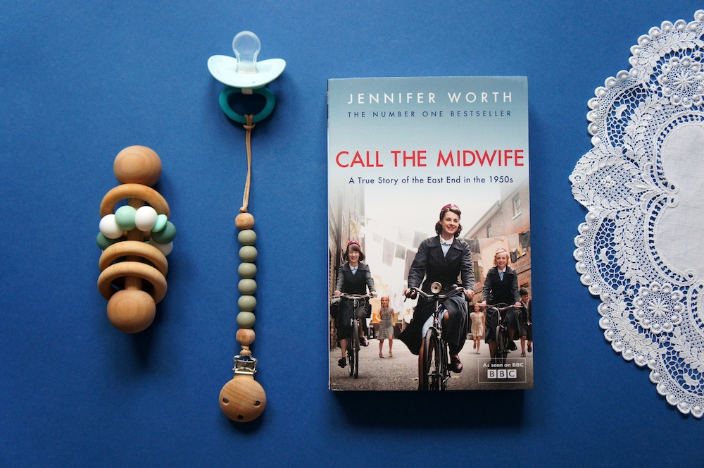 Call The Midwife book on a table with a babies wooden rattle toy and dummy
