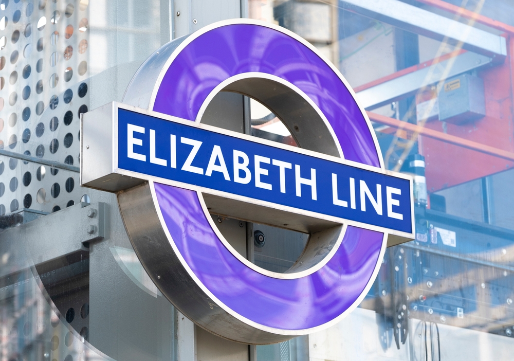 Purple tube symbol for the new Elizabeth line mounted on a glass wall of a station building