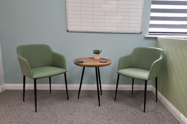 Two comfortable green chairs around a coffee table providing a calm waiting area in the Trust offices