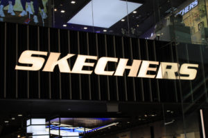 Skechers logo in large gold letters on black glass on the front of a store