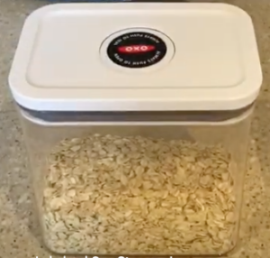 clear kitchen storage jar with a white lid holding some food