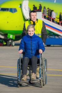Lady in a wheelchair being pushed by an attendant at an airport