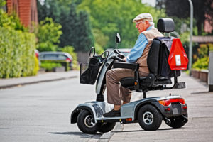 elderly man driving a mobility scooter onto the road
